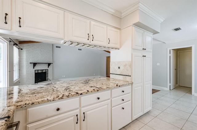 kitchen featuring white cabinetry, crown molding, light stone countertops, and light tile patterned flooring