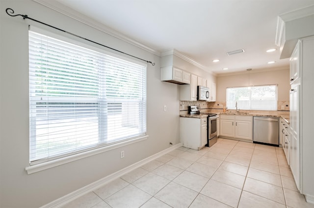 kitchen with appliances with stainless steel finishes, pendant lighting, sink, white cabinets, and crown molding