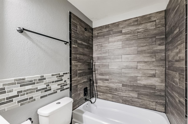 bathroom featuring toilet, tiled shower / bath combo, and tile walls