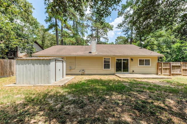 back of property with a lawn, a patio, and a storage unit