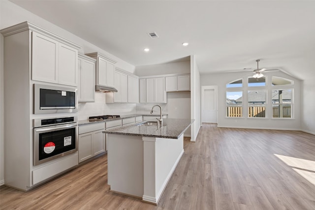 27603 Beachside Arbor Dr, Katy, TX 77493 - kitchen with stainless steel appliances, a sink, dark stone countertops, light wood-type flooring, and ceiling fan