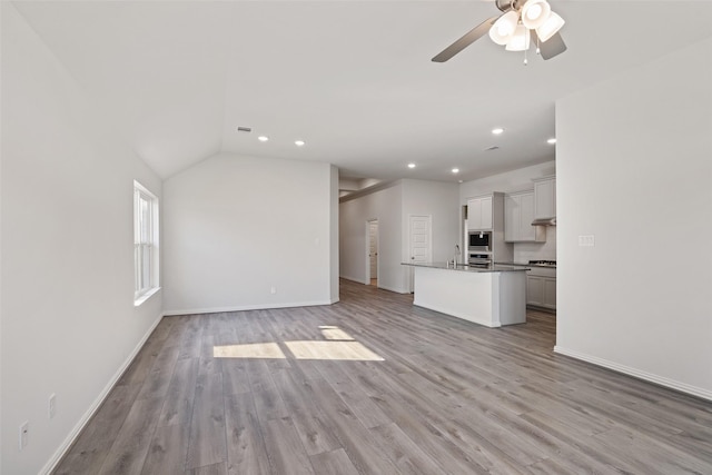 27603 Beachside Arbor Dr, Katy, TX 77493 - unfurnished living room with light wood-style flooring, ceiling fan, baseboards, recessed lighting, and a sink