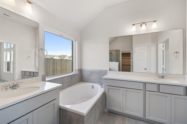 27603 Beachside Arbor Dr, Katy, TX 77493 - bathroom with vaulted ceiling, a bath, two vanities, and tile patterned floors