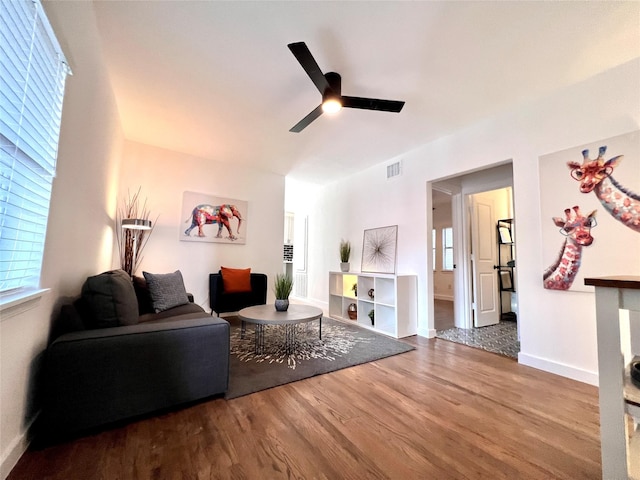 living room featuring baseboards, wood finished floors, visible vents, and a ceiling fan