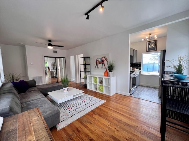 living room featuring baseboards, light wood-style flooring, visible vents, and a healthy amount of sunlight