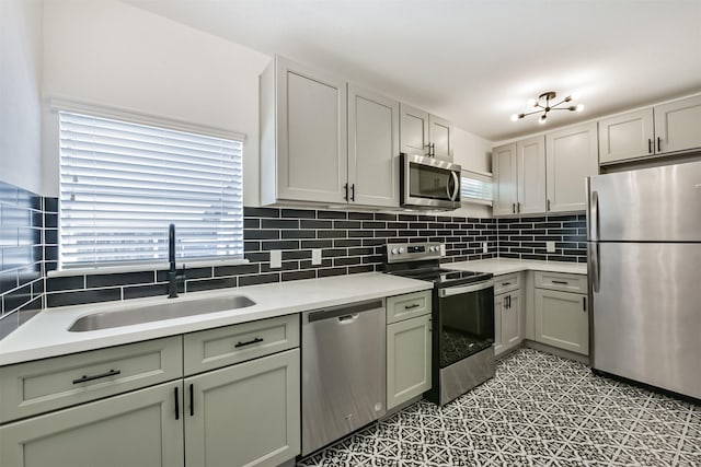 kitchen with backsplash, stainless steel appliances, light countertops, light floors, and a sink