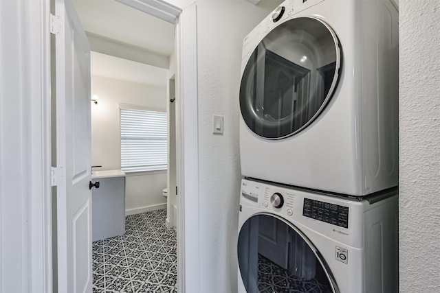 laundry room with stacked washer and clothes dryer, baseboards, and laundry area