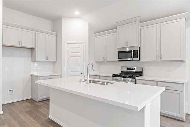 5830 Westwood Shore Dr, Katy, TX 77493 - kitchen featuring stainless steel appliances, a sink, decorative backsplash, light wood finished floors, and lofted ceiling