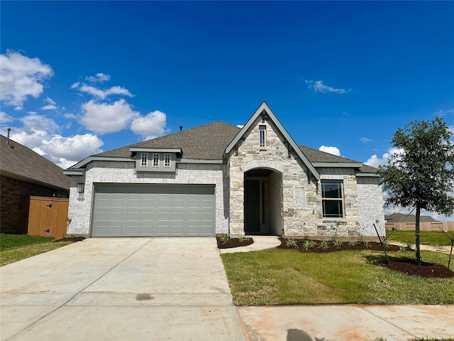 5830 Westwood Shore Dr, Katy, TX 77493 - french country style house with a garage, driveway, a front lawn, stone siding, and roof with shingles