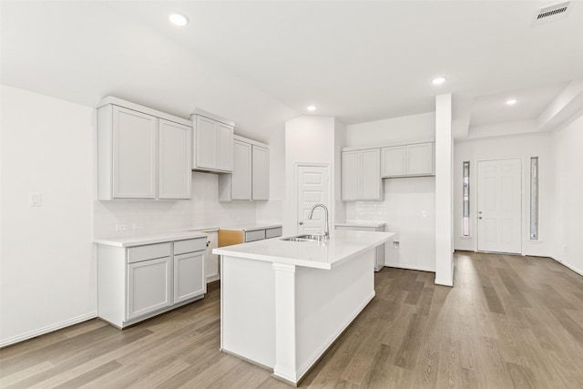 5830 Westwood Shore Dr, Katy, TX 77493 - kitchen featuring wood finished floors, a kitchen island with sink, recessed lighting, decorative backsplash, and light countertops