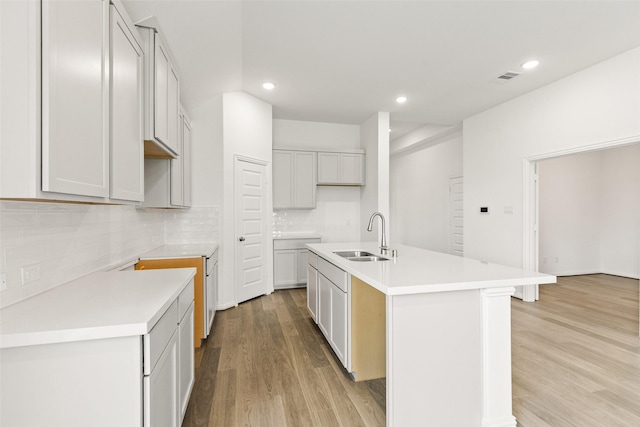 5830 Westwood Shore Dr, Katy, TX 77493 - kitchen with a center island with sink, light wood-type flooring, tasteful backsplash, recessed lighting, and light countertops