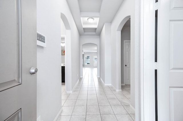 hallway with a raised ceiling and light tile patterned floors