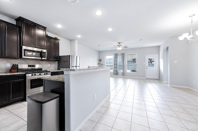 kitchen with a kitchen island, light tile patterned flooring, appliances with stainless steel finishes, and backsplash