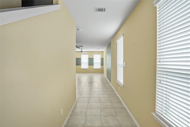 hall featuring light tile patterned flooring, visible vents, and baseboards