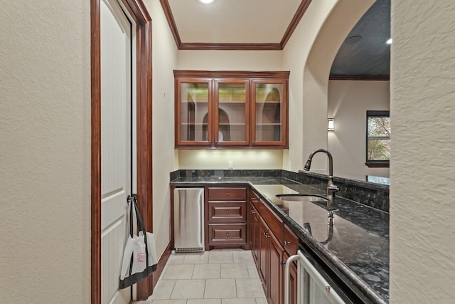 kitchen featuring sink, light tile patterned floors, dishwasher, ornamental molding, and dark stone counters