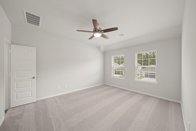 spare room featuring light colored carpet, baseboards, ceiling fan, and visible vents