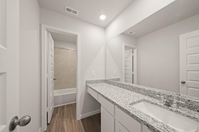 full bath featuring vanity, baseboards, visible vents, and wood finished floors