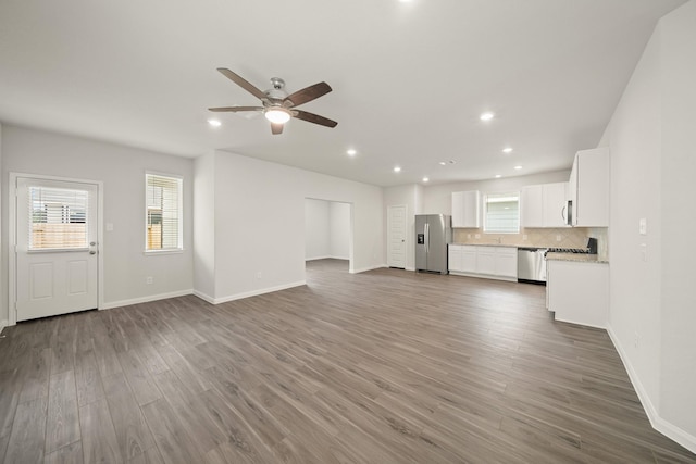 unfurnished living room featuring wood finished floors, baseboards, ceiling fan, and recessed lighting