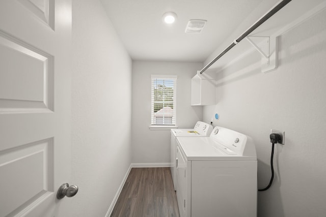 clothes washing area with laundry area, baseboards, washing machine and dryer, and dark wood-style floors