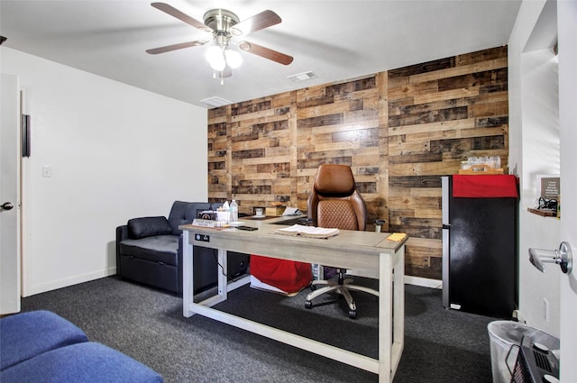 carpeted home office featuring ceiling fan and wooden walls