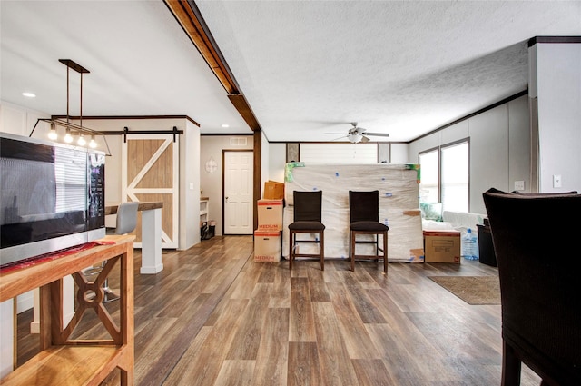 living room with crown molding, a barn door, hardwood / wood-style floors, and a textured ceiling