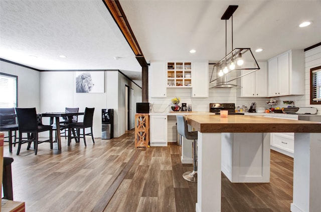 kitchen with a breakfast bar, butcher block countertops, decorative light fixtures, white cabinets, and black range with electric cooktop