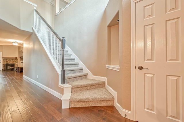 stairway with hardwood / wood-style flooring and a fireplace