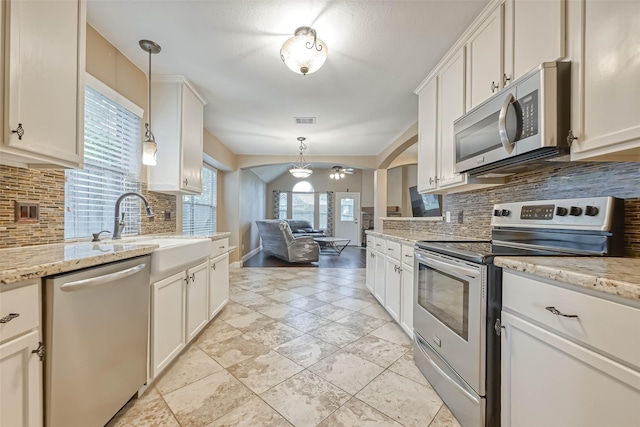 kitchen with sink, decorative light fixtures, stainless steel appliances, light stone countertops, and white cabinets