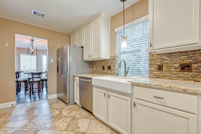 kitchen with pendant lighting, sink, white cabinetry, stainless steel appliances, and light stone counters