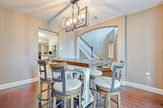 dining space with dark wood-type flooring and a notable chandelier