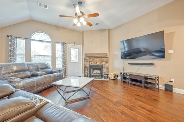 living room featuring ceiling fan, lofted ceiling, a stone fireplace, and hardwood / wood-style floors