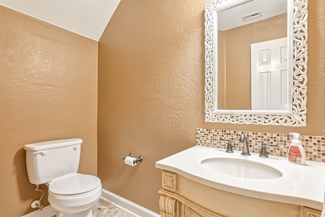 bathroom featuring tasteful backsplash, vanity, and toilet