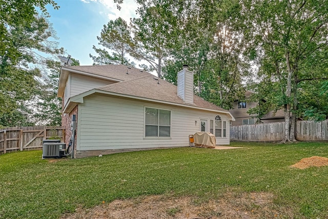 rear view of property featuring a lawn and central air condition unit