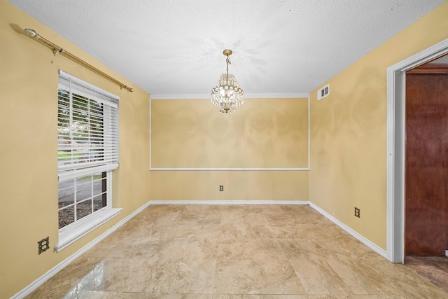 empty room with a textured ceiling and a chandelier