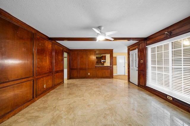 interior space featuring ceiling fan, a textured ceiling, and wood walls