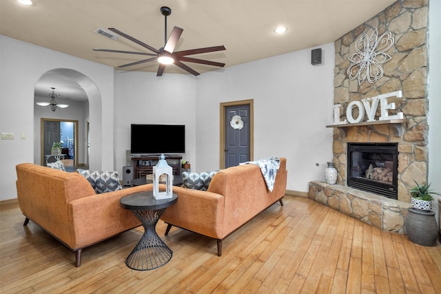 living room with arched walkways, visible vents, a fireplace, and light wood-style flooring