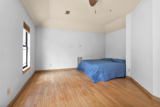 unfurnished bedroom featuring baseboards, visible vents, ceiling fan, vaulted ceiling, and light wood-type flooring