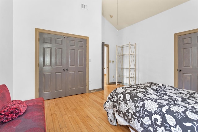 bedroom with high vaulted ceiling, baseboards, visible vents, and light wood finished floors