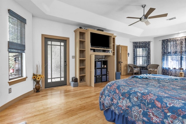 bedroom with wood finished floors, a ceiling fan, visible vents, baseboards, and a raised ceiling