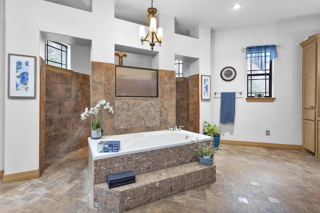 bathroom with a bath, baseboards, stone finish floor, and a wealth of natural light