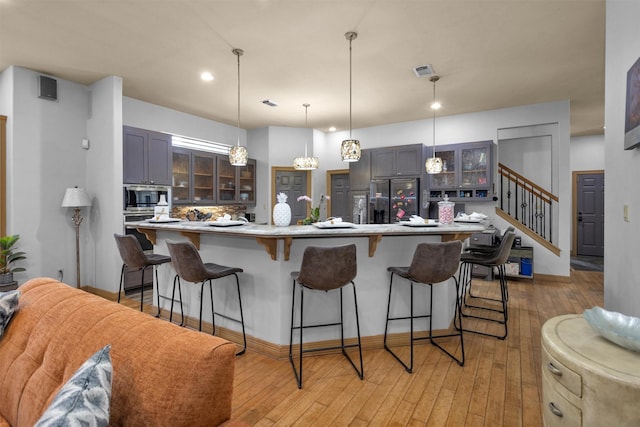 kitchen with visible vents, glass insert cabinets, a breakfast bar area, stainless steel appliances, and light countertops