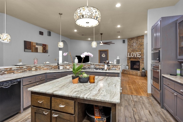 kitchen with stainless steel appliances, a center island, light wood-style floors, and a sink