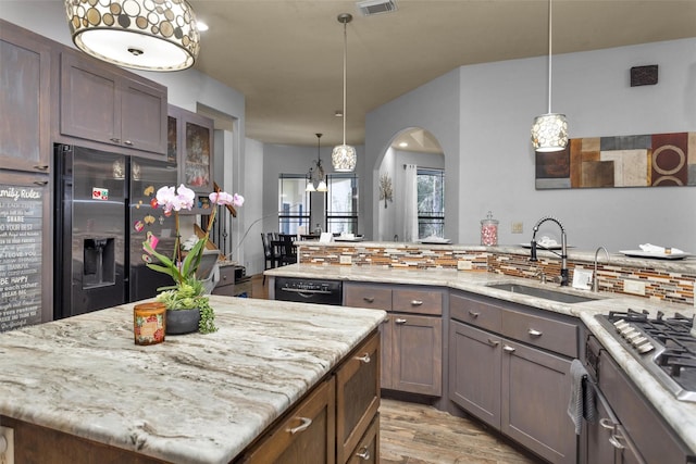 kitchen featuring light stone counters, stainless steel appliances, tasteful backsplash, light wood-style flooring, and a sink