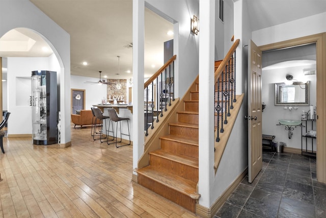 stairway featuring visible vents, baseboards, ceiling fan, and wood finished floors