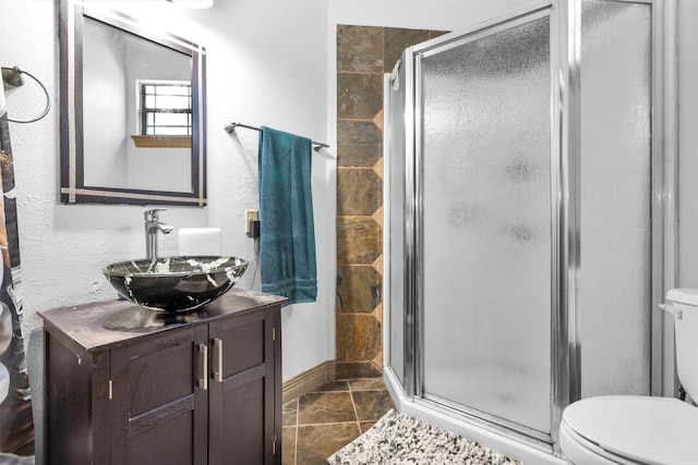 full bathroom featuring a stall shower, vanity, toilet, and baseboards