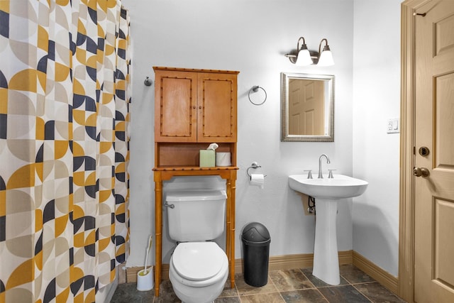 bathroom with a shower with shower curtain, toilet, and baseboards