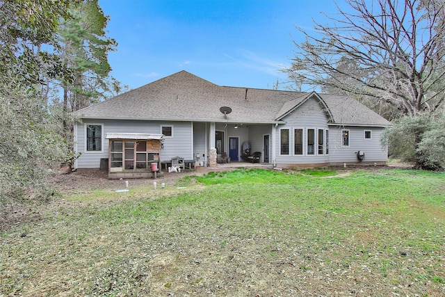 back of house with a patio area, a sunroom, roof with shingles, and a lawn