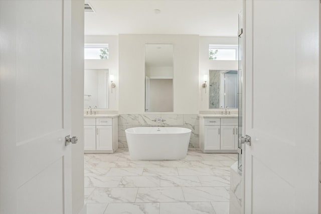 bathroom with visible vents, a soaking tub, a wainscoted wall, marble finish floor, and a sink