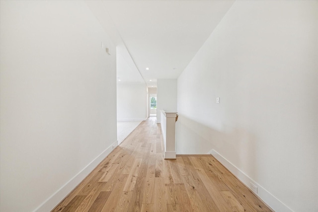 corridor with light wood-type flooring, baseboards, and recessed lighting