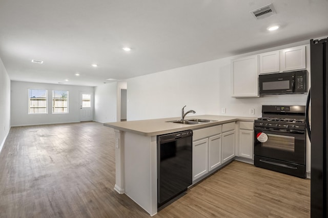 kitchen featuring white cabinetry, sink, kitchen peninsula, and black appliances